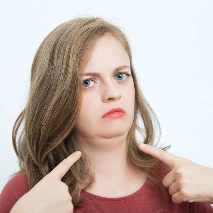 a woman pointing to her double chin.